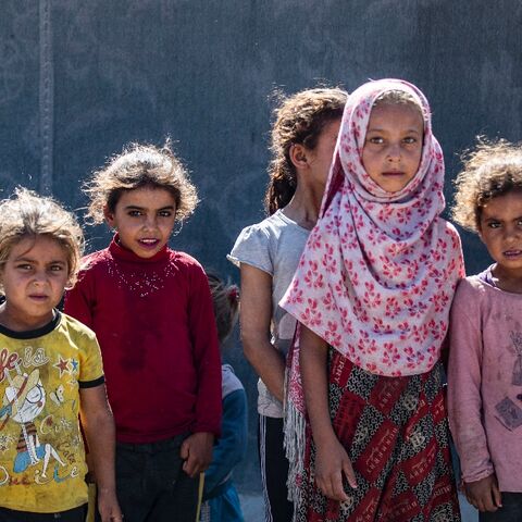 Girls stand next to a tent at the Al-Yunani makeshift camp in Syria's northern province of Raqa