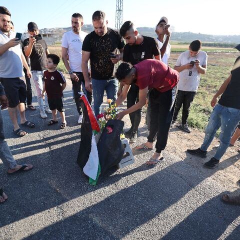 Mourners lay roses at the site where three Palestinians were killed by Israeli forces near Jenin camp in the occupied West Bank