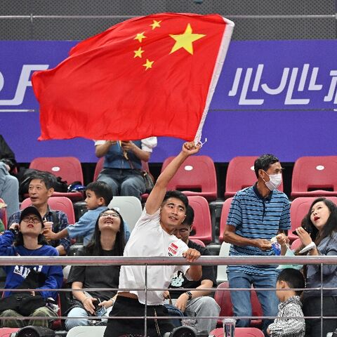 A man waves a Chinese flag as he watches the women's table tennis team