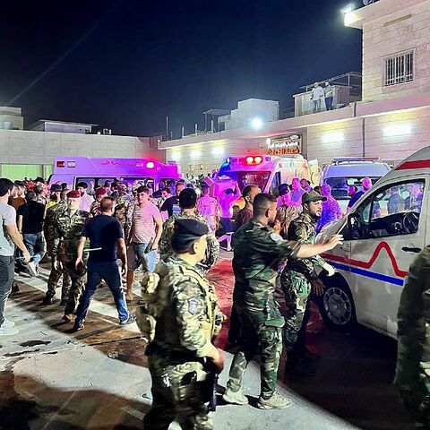 Soldiers and emergency responders gather around ambulances carrying people injured in a fire at an Iraqi wedding