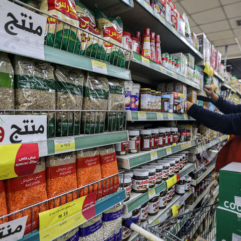 A worker arranges products on a shelf as nearby labels reading in Arabic "national product" are displayed on packaged items at a supermarket in Ramallah in the occupied West Bank on December 26, 2023, as part of a wider campaign urging Palestinians to boycott Israeli products and buy locally made goods. Since the war in Gaza began, a slew of boycott posters, stickers and leaflets has cropped up across the occupied West Bank. Many Palestinians are looking for alternatives as calls to ban Israeli goods also g