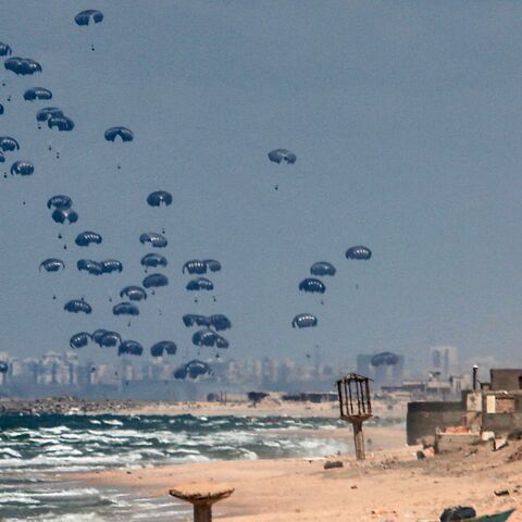 Humanitarian aid is dropped on the Gaza Strip, west of Gaza City, on March 25, 2024, amid the ongoing conflict in the Palestinian territory between Israel and the militant group Hamas, with the background showing Israel's Rutenberg power station near Ashkelon.
