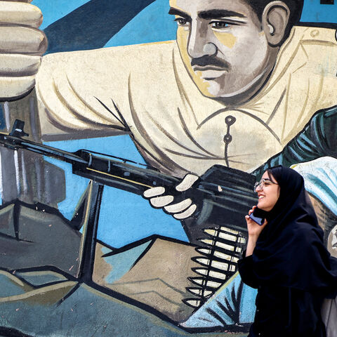A woman walks past an anti-Israeli mural depicting fighters with assault rifles along a wall in Palestine Square in Tehran on April 14, 2024. Iran on April 14 urged Israel not to retaliate militarily to an unprecedented attack overnight, which Tehran presented as a justified response to a deadly strike on its consulate building in Damascus. (Photo by ATTA KENARE / AFP) (Photo by ATTA KENARE/AFP via Getty Images)