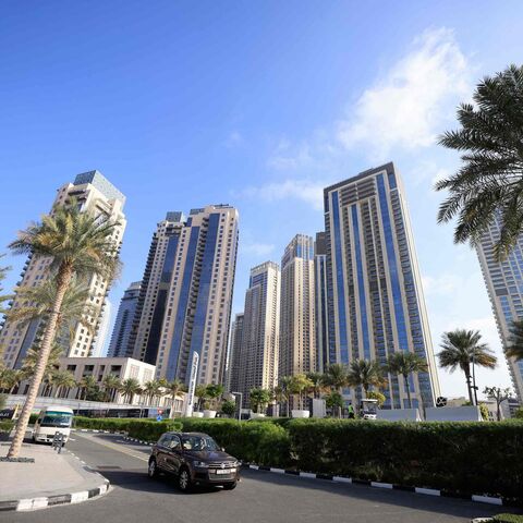 Cars drive along a street in front of high-rise buildings in Dubai, on February 18, 2023. - Home to towering skyscrapers and ultra-luxury villas, Dubai saw record real estate transactions in 2022, largely due to an influx of wealthy investors, especially from Russia. (Photo by Karim SAHIB / AFP) (Photo by KARIM SAHIB/AFP via Getty Images)
