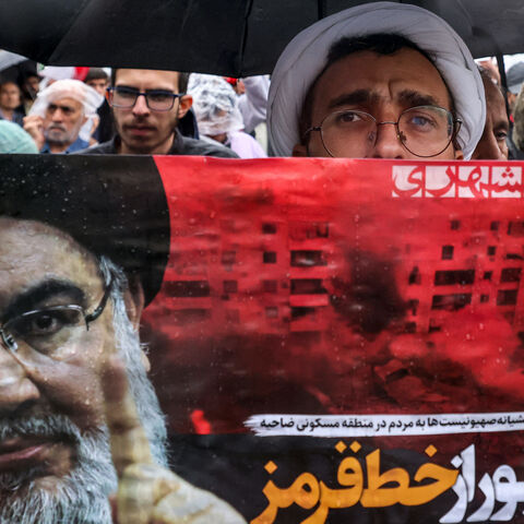 A Shiite Muslim cleric holds a poster reading "crossing a red line" in Persian next to an image of Hassan Nasrallah, the late leader of the Lebanese Hezbollah group, during an anti-Israel protest in Tehran's Palestine Square on Sept. 28, 2024, after Hezbollah confirmed reports of Nasrallah's killing in an Israeli air strike in Beirut the previous day. 