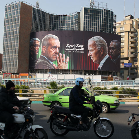 Commuters drive past a billboard bearing pictures of Iran's President Masoud Pezeshkian (2-L), armed forces chief of staff Major General Mohammad Bagheri (L) US President Joe Biden (2-R) and Israeli Prime Minister Benjamin Netanyahu (R) in Vali-Asr square in Tehran on Oct. 27, 2024.