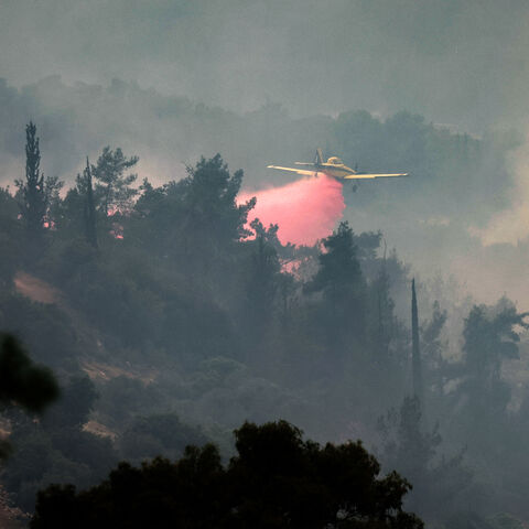An Air Tractor AT-802AF firefighting aircraft drops flame retardant while trying to extinguish a forest fire near the central Israeli town of Bet Shemesh, near Jerusalem on April 23, 2025. (Photo by Ahmad GHARABLI / AFP) (Photo by AHMAD GHARABLI/AFP via Getty Images)