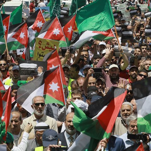 Flags of Jordan and the Muslim Brotherhood are waved with other protest signs denouncing the US-led Middle East economic conference in Bahrain, in the Jordanian capital, Amman, on June 21, 2019. 
