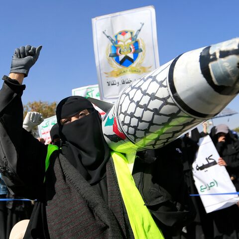 A Yemeni woman holds up a mock missile decorated with the colors of the Palestinian flag and the checkered keffiyeh during a protest in Sanaa to denounce strikes on Yemen and Israel's bombardment of Gaza, on Jan. 15, 2025.