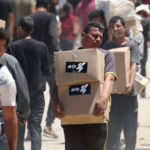 People carry boxes of relief supplies from the Gaza Humanitarian Foundation (GHF) as displaced Palestinians return from an aid distribution center in the central Gaza Strip on May 29, 2025. 