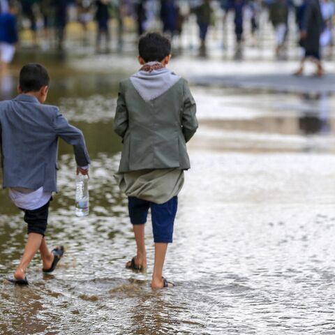 Yemeni boys walk on a flooded road during a rally in solidarity with Palestinians in the Houthi-run capital Sanaa on Aug. 1, 2025.