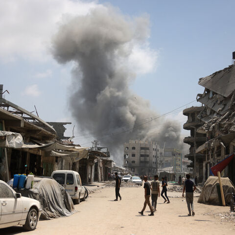 Palestinians watch as a plume of smoke rises during an Israeli strike on Gaza City's southern al-Zeitoun neighbourhood on Aug. 8, 2025. 
