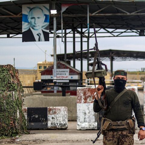 A Syrian rebel fighter looks on as he stands at an inspection checkpoint for incoming vehicles at the entrance of the Russian-leased Syrian military base of Hmeimim in Latakia province in western Syria on Dec. 29, 2024. 