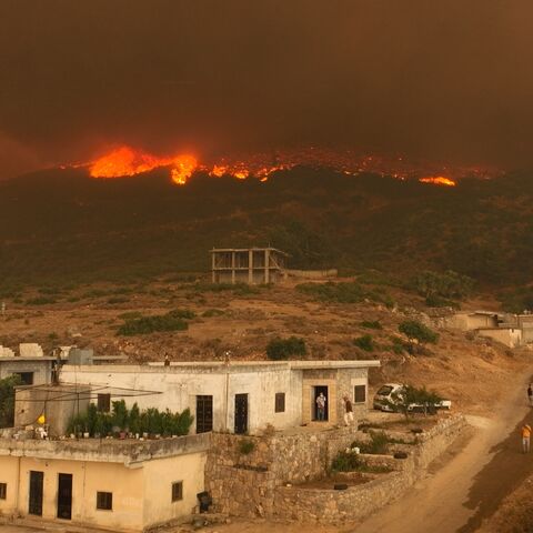 Residents of the village of Shatha watch as a wildfire rages on the nearby hills, in the western Hama countryside in west-central Syria on Aug. 15, 2025.