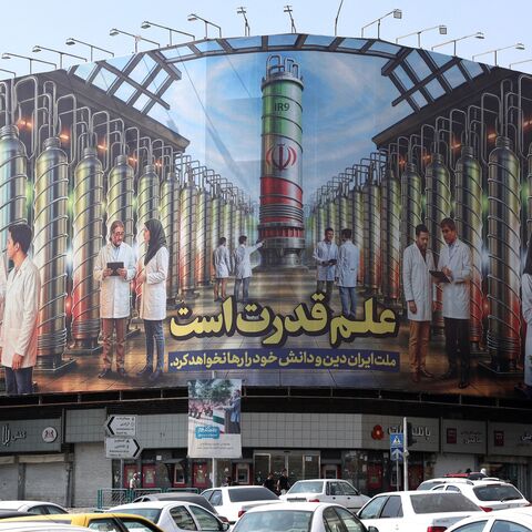 Iranians drive next to a billboard displaying pictures of nuclear scientists, centrifuges and a sentence reading in Farsi, "Science is the power," at the Enqelab Square in Tehran, on Aug. 29, 2025.