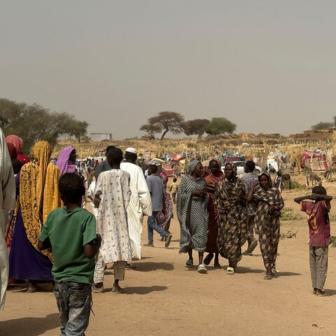 People who fled the Zamzam camp for the internally displaced after it fell under RSF control walk in a makeshift encampment in an open field near the town of Tawila in war-torn Sudan's western Darfur region on April 13, 2025. 