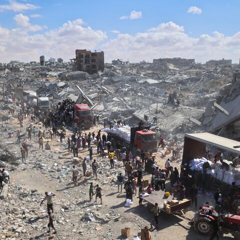 Palestinians rally around aid trucks which entered from the Karem Abu Salem crossing, in Khan Yunis in the southern Gaza Strip on Oct. 12, 2025.
