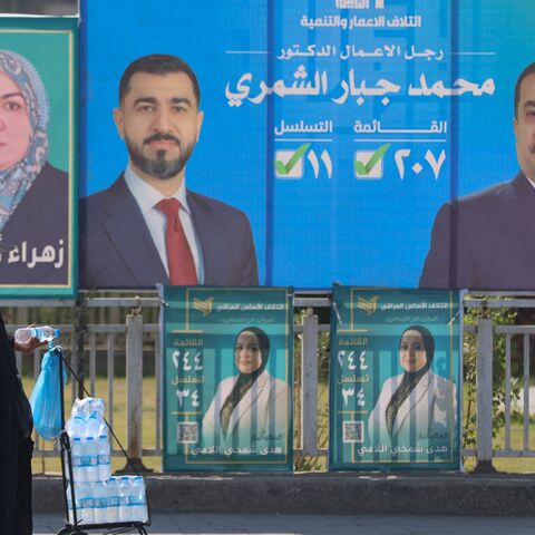 A woman walks past electoral billboards in central Baghdad on Oct. 19, 2025, ahead of parliamentary elections in Iraq on Nov. 11.