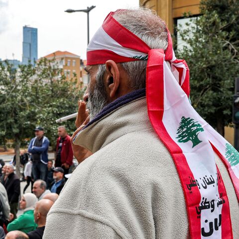 A demonstrator wearing a bandana in the colours of the Lebanese flag smokes a cigarette as retired Lebanese army and security forces veterans gather to protest outside the government palace headquarters in the centre of Beirut on March 22, 2023, demanding inflation-adjustments to their pensions. (Photo by Joseph EID / AFP) (Photo by JOSEPH EID/AFP via Getty Images)