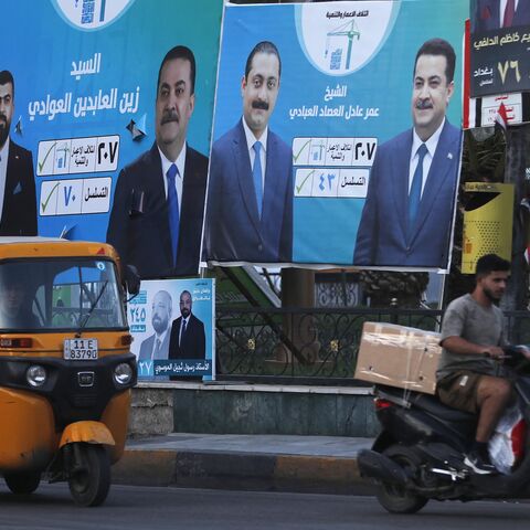 People drive past election billboards in Baghdad, Oct. 14, 2025. 