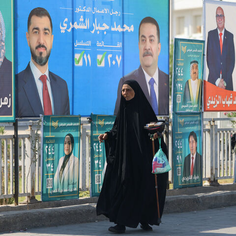 Iraqis walk past electoral billboards, including one bearing a portrait of Prime Minister Mohammed Shia al-Sudani (C), in central Baghdad on Oct. 19, 2025, ahead of Iraq's parliamentary elections on Nov. 11. 