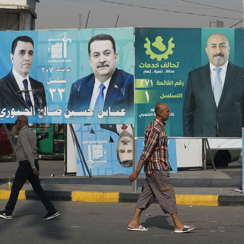People walk past electoral campaign posters ahead of Iraq's parliamentary elections in central Baghdad on Nov. 6, 2025. 