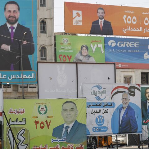 People walk past electoral campaign posters ahead of Iraq's parliamentary elections in central Baghdad on Nov. 6, 2025. 