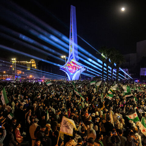 TOPSHOT - This aerial view shows people gathering to commemorate the 14th anniversary of the uprising against Syria's former president Bashar al-Assad for the first time since he was toppled in the Umayyad Square in the centre of Damascus on March 15, 2025. The rally in Damascus was the capital's first after years of repression under Assad, during which the square was the sole preserve of the ousted president's supporters. Activists called on people to hold similar demonstrations in the major cities of Homs