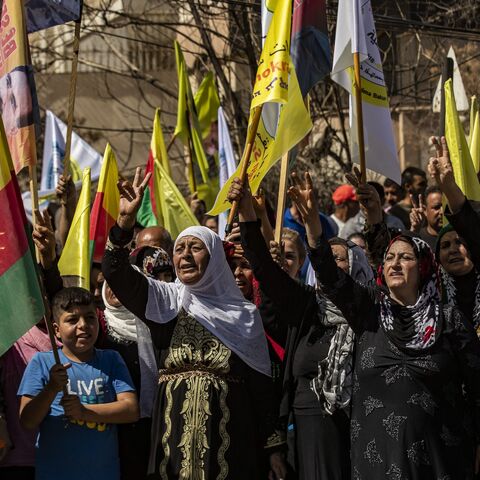 Syrian Kurds lift placards and flags during a rally calling for an autonomous administration and Kurdish rights in Syria's predominantly Kurdish northeastern city of Qamishli, on Sept. 17, 2025.