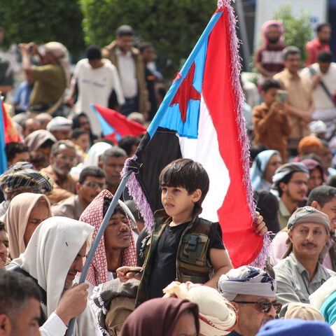 A boy looks on as supporters of the Southern Transitional Council (STC), a coalition of separatist groups seeking to restore the state of South Yemen, hold South Yemen flags during a rally calling for the revival of the former independent state, in Aden on December 12, 2025. The UAE-backed Southern Transitional Council last week swept through swathes of Yemen in a near-bloodless takeover they say aimed to expel Islamists and halt smuggling for the benefit of the Iran-backed Houthis. (Photo by Saleh Al-OBEID