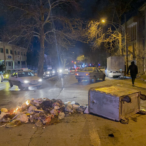 Burning debris lies next to an overturned dumpster in the middle of a street during unrest amid demonstrations in Hamedan, Iran, on January 1, 2026. The demonstrations erupted after shopkeepers in Tehran's Grand Bazaar shut their businesses to protest the sharp fall of Iran's currency and worsening economic conditions, with clashes reported in several provinces and Iranian media and rights groups saying multiple people were killed in the violence, marking the largest protests to hit the Islamic Republic in 