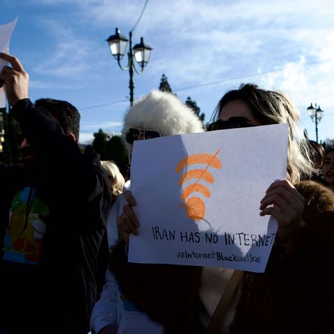 Backlit image of Iranian demonstrators holding national flags and portraits during an antiKhamenei protest at Syntagma Square in Athens, Greece, on January 11, 2026. What stands out is a woman holding a placard featuring a Wi Fi symbol and the message "Iran has no internet," referencing an internet blackout in Iran. The gathering takes place in front of the Hellenic Parliament, where protesters primarily supporters of the former Shah express opposition to the current Iranian regime and denounce restrictions