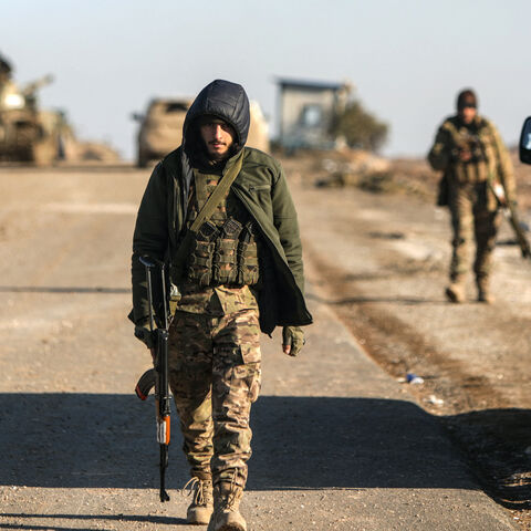 Soldiers walk past a parked car as Syrian government forces make their way to the city of Hasakeh in northeastern Syria on Jan. 20, 2026.