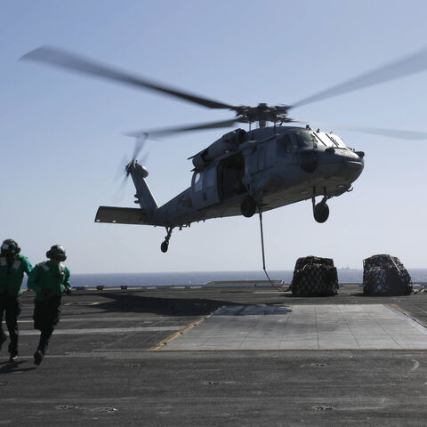 In this handout photo provided by the US Navy, Logistics Specialist 1st Class Ousseinou Kaba (left), from Silver Spring, Md., and Logistics Specialist Seaman Abigail Marshke, from Flint, Mich., attach cargo to an MH-60S Sea Hawk helicopter from the "Nightdippers" of Helicopter Sea Combat Squadron (HSC) 5 from the flight deck of the Nimitz-class aircraft carrier USS Abraham Lincoln (CVN 72) May 10, 2019 in the Red Sea.