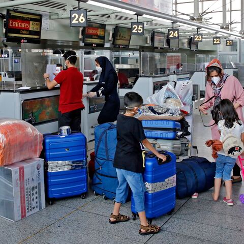 Outbound passengers arrive with their luggage at the Emirates check-in counter at the Iranian capital Tehran's Imam Khomeini International Airport, on July 17, 2020.