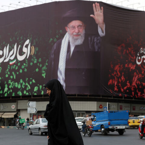 TOPSHOT - An Iranian crosses a street next to a billboard bearing the portrait of Iranian supreme leader Ayatollah Ali Khamenei and a quote reads in Persian 'Sing Oh Iran' at the Enqelab Square in Tehran on July, 9, 2025. (Photo by AFP) (Photo by -/AFP via Getty Images)
