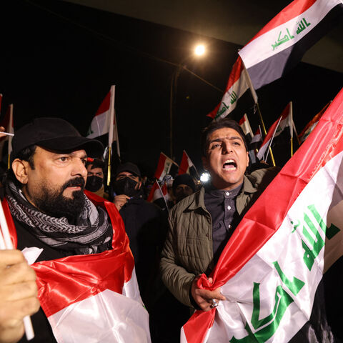 Iraqis raise their flags during a protest at the entrance to the Hanging Bridge, one of the entrances to the Green Zone in Baghdad on Jan. 28, 2026.  