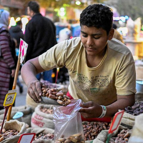 An Egyptian vendor fills dates for a customer at a market in Cairo's central Sayyida Zeinab district on Feb. 12, 2026, as Muslims prepare for the holy fasting month of Ramadan, which begins early next week. 