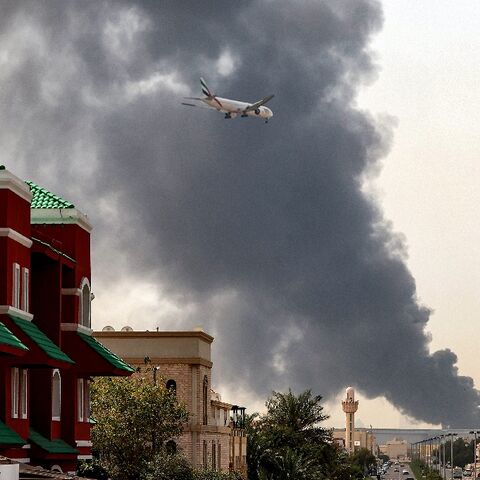 A plane comes into land as smoke rises near Dubai International Airport 