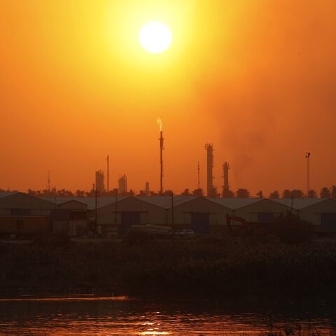 The sun sets behind burning gas flares at the Dora Oil Refinery Complex in Baghdad on Nov. 24, 2025. 