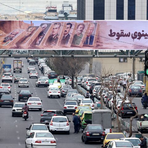 Traffic rolls along a main throughfare under a banner with images of past and present leaders that reads in Farsi, "Domino fall", as daily life returns to the streets following nationwide protests, in the Iranian capital Tehran on January 19, 2026. Demonstrations sparked in late December by anger over economic hardship exploded into protests widely seen as the biggest challenge to the Iranian leadership in years. Limited internet access briefly returned in Iran before dropping again, a monitor said January 