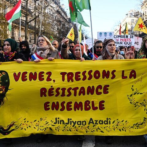 Protesters hold a banner reading "Come and weave resistance together" and "Women, life, freedom." 