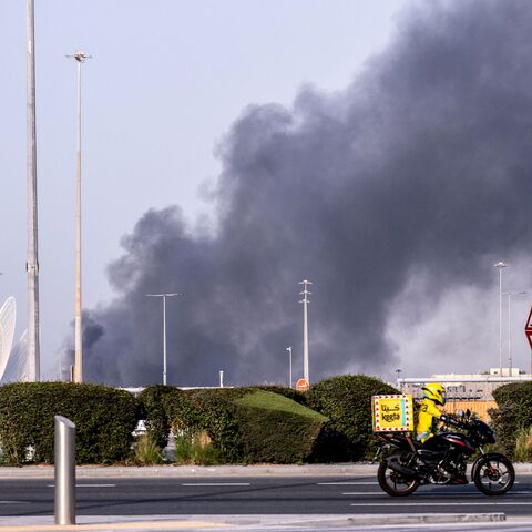 A food delivery bike drive close to a plume of smoke rising from the Zayed Port following a reported Iranian strike in Abu Dhabi on March 1, 2026. Iran's retaliatory missile and drone campaign in the Gulf has killed three people and wounded 58 in the United Arab Emirates since it began, Emirati authorities said on March 1, the day after the US and Israel launched a nationwaide attack on Iran killing its supreme leader. (Photo by Ryan Lim / AFP via Getty Images)
