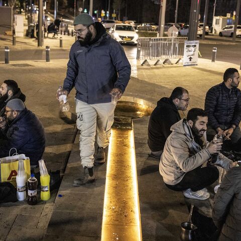 Muslim worshippers break their fast outside the old city walls of Jerusalem on March 17, 2026, as the Al-Aqsa Mosque compound remains closed. 