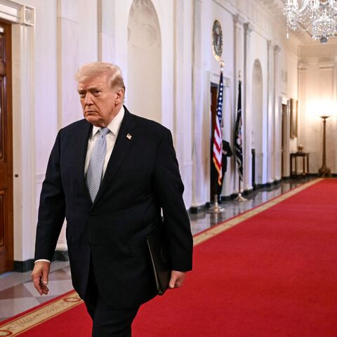 US President Donald Trump walks through the Cross Hall as he arrives for a ceremony to present the Commander-in-Chief Trophy to the Navy Midshipmen football team of the United States Naval Academy in the East Room of the White House in Washington, DC, on March 20, 2026. (Photo by Brendan SMIALOWSKI / AFP via Getty Images)