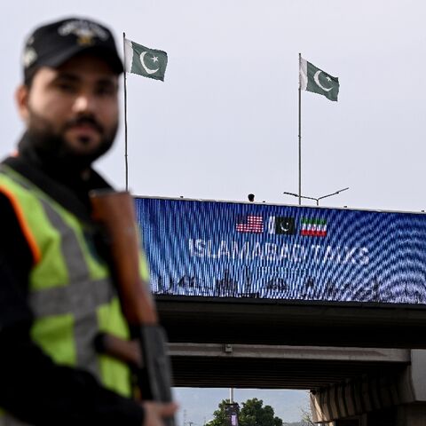 A policeman stands guard in front of a digital screen displaying news of US–Iran peace talks along a road in Pakistan's capital Islamabad