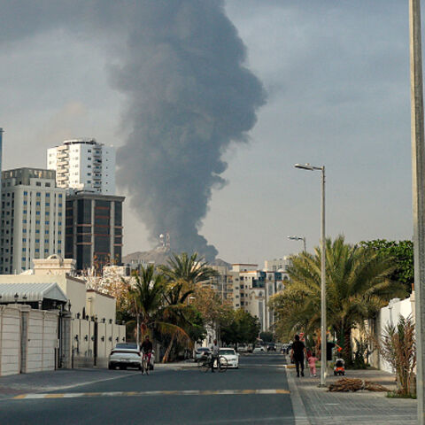 TOPSHOT - People watch from a street as a tall smoke plume billows following an explosion in the Fujairah industrial zone on March 3, 2026. Iran's strikes on Gulf neighbours since February 28, following the US-Israeli attack, forced the UAE to shut its airspace, blindsiding travellers who thought they were headed to one of the region's safest holiday destinations. (Photo by Fadel SENNA / AFP via Getty Images)