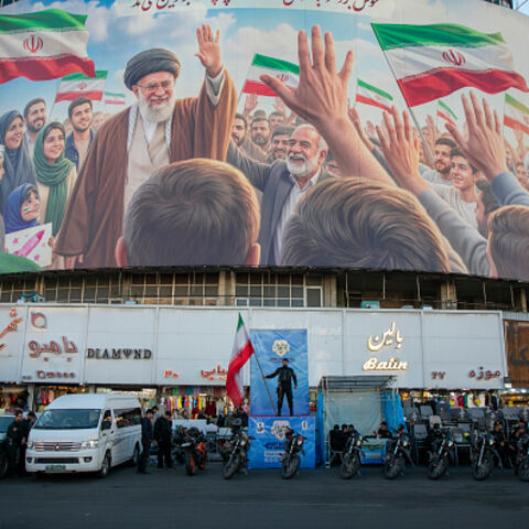 TEHRAN, IRAN - APRIL 23: A police officer stands holding a flag in Valiasr Square beneath a mural of the late Ayatollah Ali Khamenei on April 23, 2026 in Tehran, Iran. Earlier this week, U.S. President Donald Trump announced an extension of the current ceasefire between his country and Iran, despite Iran declining to attend the latest proposed round of peace talks in Islamabad. The focus of the war has shifted largely to the Strait of Hormuz, where both sides are trying to assert control over the critical m