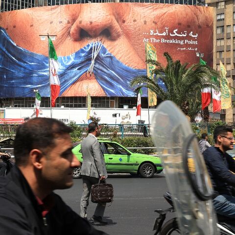 Commuters make their way past an anti-US billboard referring to President Donald Trump and the Strait of Hormuz, installed on a building at the Valiasr Square in Tehran