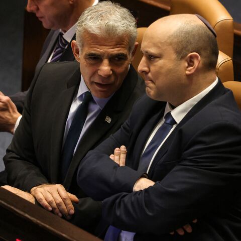 Israeli Minister of Foreign Affairs Yair Lapid (L) speaks to outgoing Prime Minister Naftali Bennett, during a meeting at the Knesset (parliament), in Jerusalem on June 30, 2022. - Final approval of the parliament dissolution bill was initially expected by midnight but was postponed to June 30 as coalition and opposition lawmakers sparred over last-minute legislative details, several sources familiar with the parliamentary said. (Photo by Menahem KAHANA / AFP) (Photo by MENAHEM KAHANA/AFP via Getty Images)